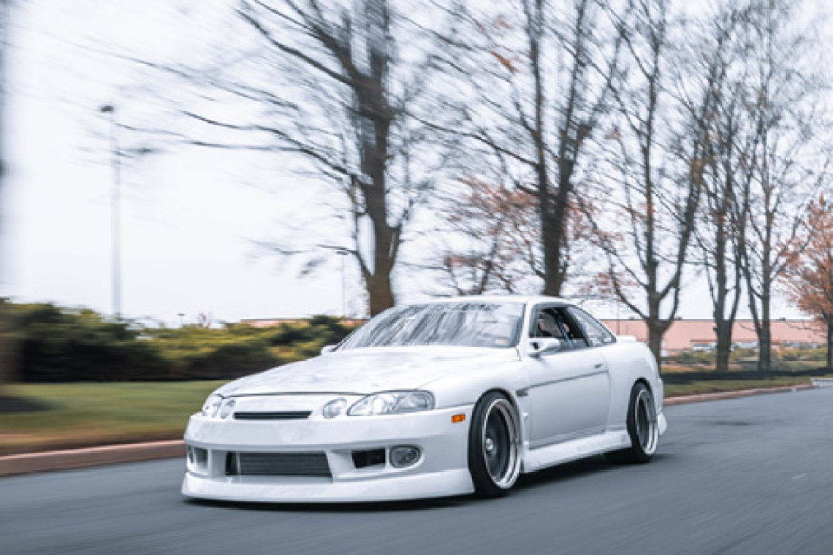 Aum Sung’s white 1992 Lexus SC400 cruising on the street with BN Sports widebody styling and Work Meister wheels.
